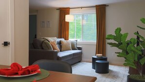 A living room with a grey sofa, a dining table with a red napkin, and a potted plant. - The Green Mountain Escape ~ Near Trails & Lake (Colchester)