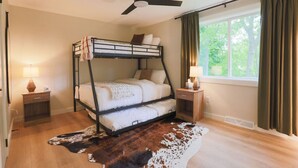 A bunk bed room with a ceiling fan, bedside tables with lamps, a cowhide rug, and a window with curtains. - The Green Mountain Escape ~ Near Trails & Lake (Colchester)