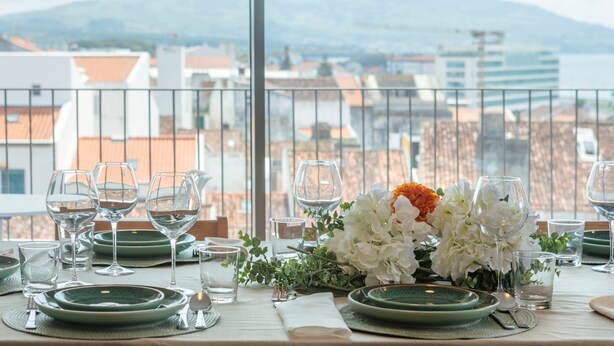 A table set for dining with a view of buildings and mountains in the background. - URBAN PENTHOUSE by Azores HomeMade (Ponta Delgada)
