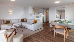 A modern living room with a white sofa, a dining table set for four, and a wooden floor. - URBAN PENTHOUSE by Azores HomeMade (Ponta Delgada)