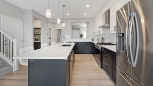 A modern kitchen with a central island, stainless steel appliances, and pendant lighting. - Luxury 5BR House for Large Groups & Families | Cozy Home in Calgary (Calgary)