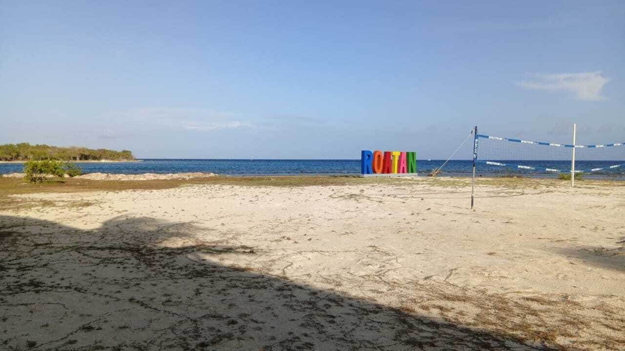 Uma quadra de voleibol de praia, com rede e uma placa com a palavra 'ROTHAN'.