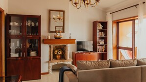 Ein Wohnzimmer mit Kamin, Fernseher, Sofa und Holzelementen.