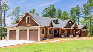Une grande maison à deux étages, avec une façade en briques et plusieurs portes de garage.