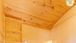 A wooden room with a bed, a ladder, and wall-mounted lights. - La P'tiote Roulotte - MOUTHIER EN BRESSE (MOUTHIER EN BRESSE)