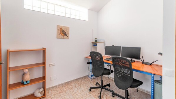 A small office space with a desk, two chairs, a shelf with a stuffed toy, and a painting on the wall. - Paraiso d'Oliva Sayalonga by Ruralidays (Málaga)