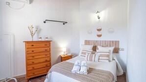 Ein Schlafzimmer mit einem Holzk dresser, einem Bett mit gestreiften Kissen, einem Nachttisch mit Lampe und einem an der Wand befestigten Regal.