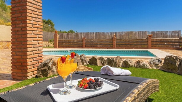 Ein Poolbereich mit Tisch, Getränken und Obst.