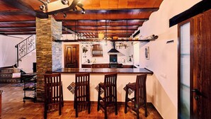 A kitchen with a central island, wooden chairs, and a hanging light fixture.