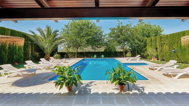 A rectangular pool with a tiled edge, surrounded by lounge chairs and potted plants.