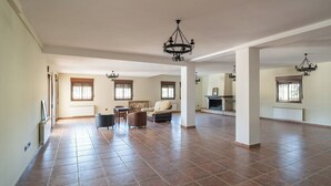 Ein geräumiges Wohnzimmer mit Kamin, großen Fenstern und hohen Decken.