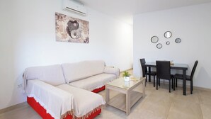 A living room with a sofa, a coffee table, and a dining area with chairs and a table. - Casa Álvaro Conil Conil de la Frontera by Ruralidays (Cádiz)