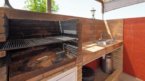 A brick-built outdoor grill with a metal grate, a sink, and a trash can. - Casa Álvaro Conil Conil de la Frontera by Ruralidays (Cádiz)