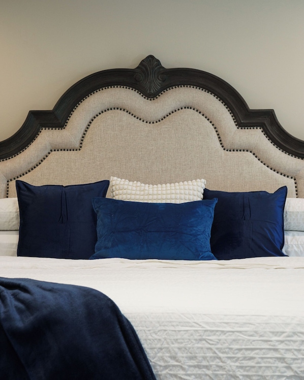 A bed with a dark headboard, multiple pillows, and a white bedspread.