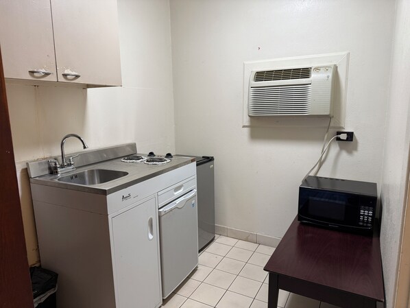 A compact kitchenette with a stove, sink, and microwave.