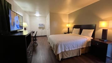 A hotel room with a bed, bedside lamps, a TV, a desk, and a chair.