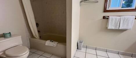 A bathroom with a toilet, a bathtub, a shower, a towel rack, and a window.