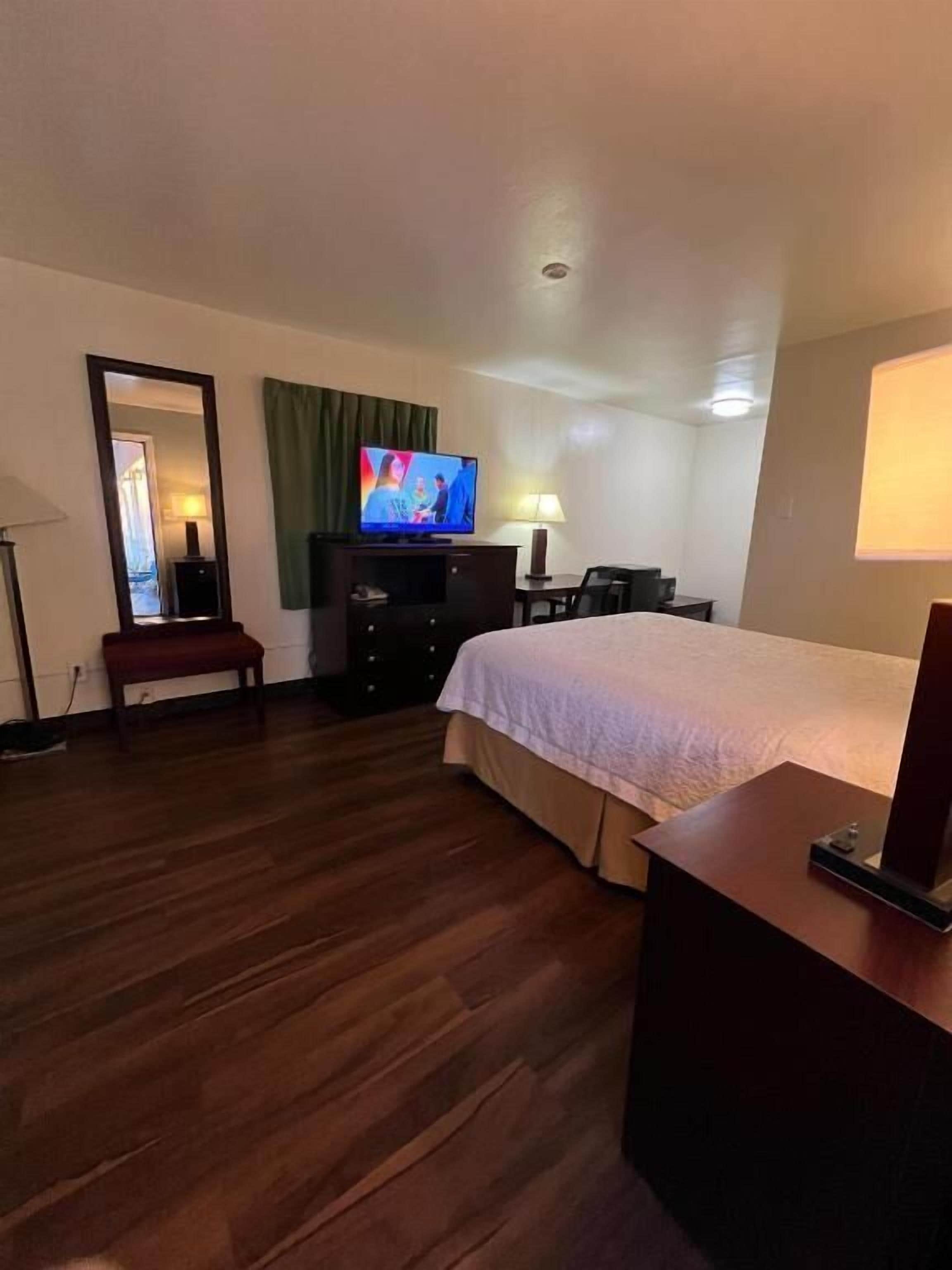Una habitación de hotel con cama, televisión, escritorio, silla y lámpara.