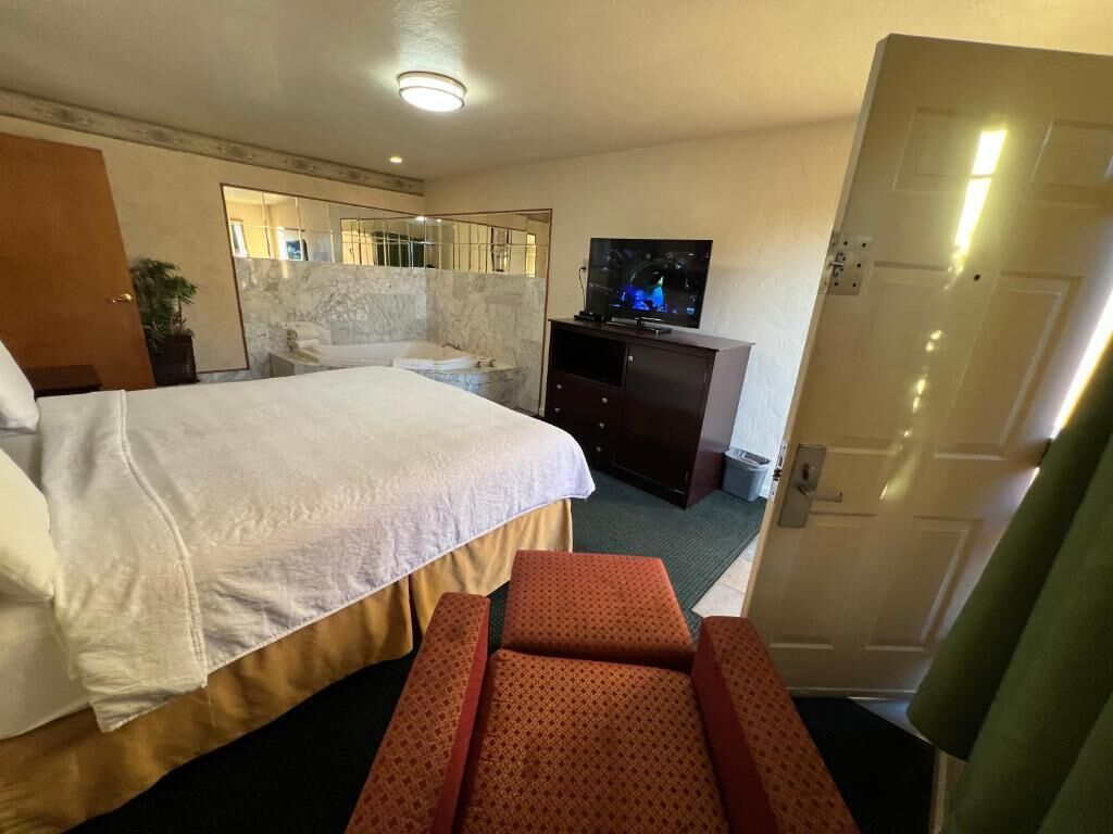 Una habitación de hotel con una cama grande, un televisor, un aparador y una puerta.