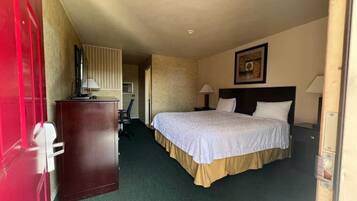 A hotel room with a bed, bedside lamps, a desk with a lamp, and a door.