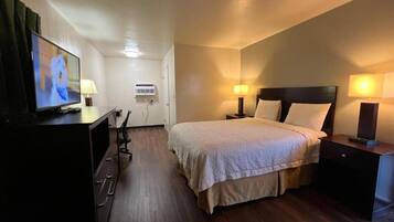 Ein Hotelzimmer mit Bett, Nachttischlampen, Fernseher, Schreibtisch und Stuhl.