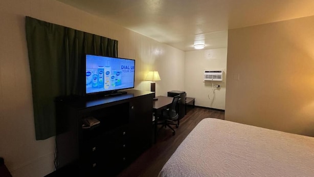 Una habitación de hotel con una cama, un televisor en una cómoda, un escritorio y una silla.