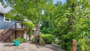 A residential property with a covered outdoor staircase, a concrete pathway, and lush greenery.