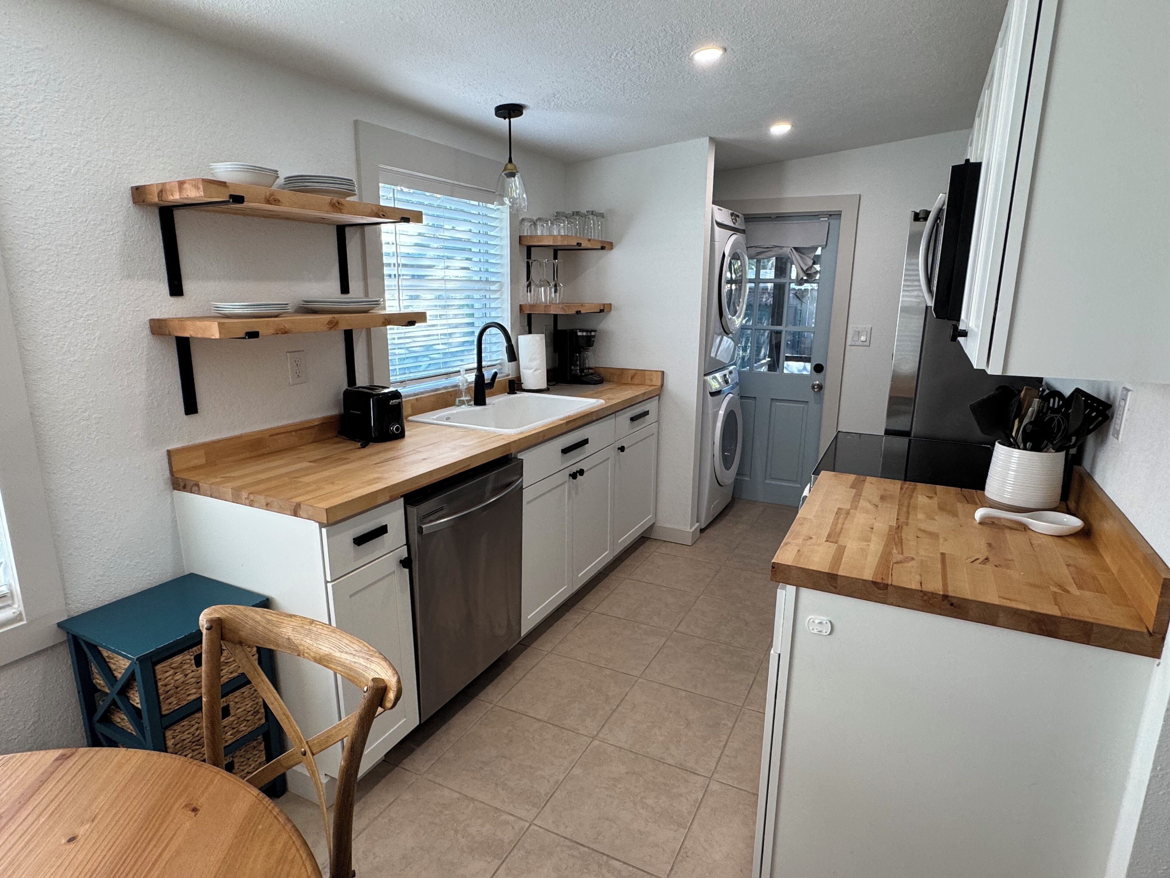 A compact kitchen with wooden countertops, a dishwasher, a sink, and a washing machine.