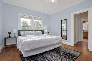 Une chambre avec un grand lit, deux tables de chevet, un miroir et une vue sur la salle de bain.