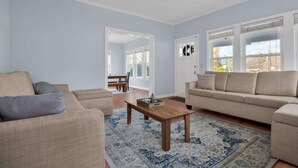 Ein Wohnzimmer mit einem beigen Sofa, einem Holztisch und einem gemusterten Teppich.