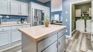 A kitchen with light blue cabinets, a granite countertop, and a refrigerator.