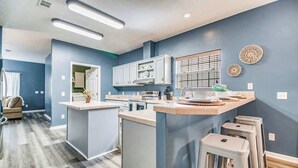 A modern kitchen with grey cabinets, a central island, and bar stools.
