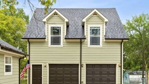 A two-story house with a garage, a front door, and an American flag.