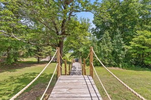 A wooden suspension bridge in a park with trees on both sides.