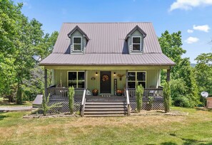 A two-story house with a front porch, a 'WELCOME' sign, and a mailbox.