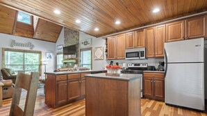 A spacious kitchen with wooden cabinets, a central island, and a refrigerator. - Updated Cabin - Hiwassee Highlife (Decatur)