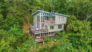 A multi-story house surrounded by dense forest.