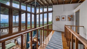 A spacious room with large windows, a wooden staircase, and a view of the outdoors.