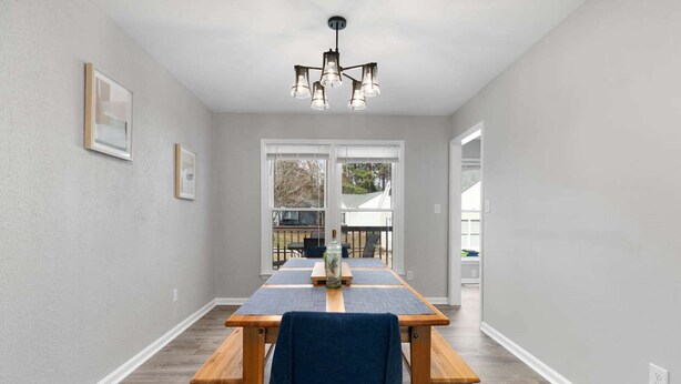 A dining area with a long table, benches, and a chandelier. - Near NC State Campus & Downtown - The Maple Marvel (Raleigh)