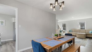 A dining area with a wooden table, chairs, and a bench. There is a sofa and a window in the background. - Near NC State Campus & Downtown - The Maple Marvel (Raleigh)