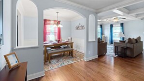 A dining area with a wooden table and bench, a chandelier, and a wall-mounted sign that reads "FAMILY".
