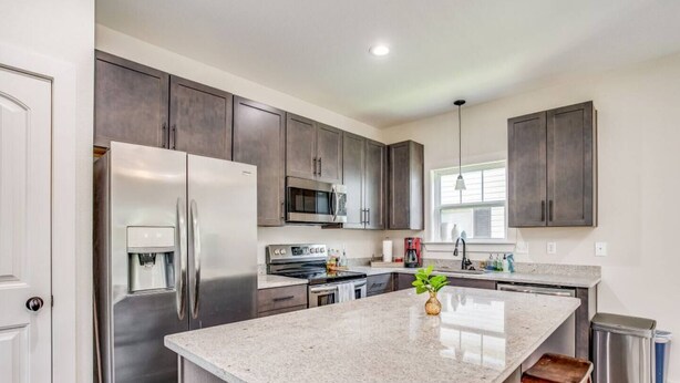 A modern kitchen with stainless steel appliances, granite countertops, and dark cabinetry. - Near Downtown, Dining & Base - Beach Flow Bungalow (Pensacola)