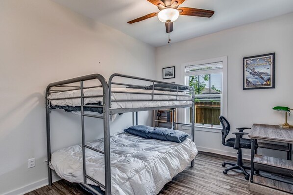 A bunk bed room with a desk, chair, and ceiling fan.