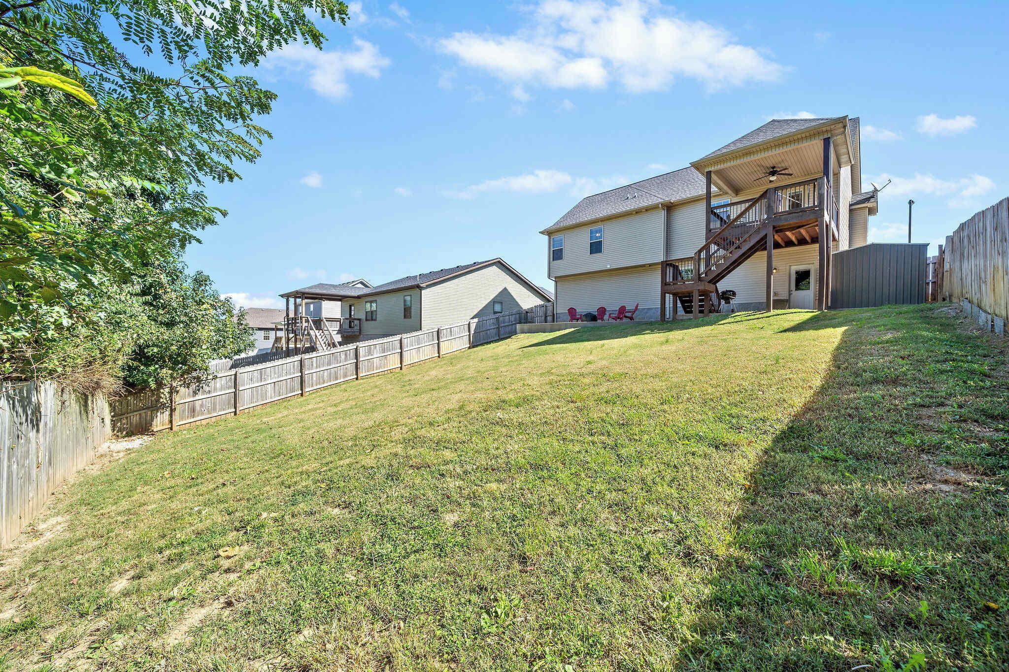 Ein zweistöckiges Haus mit überdachter Terrasse und einer Treppe, die zu der oberen Etage führt.