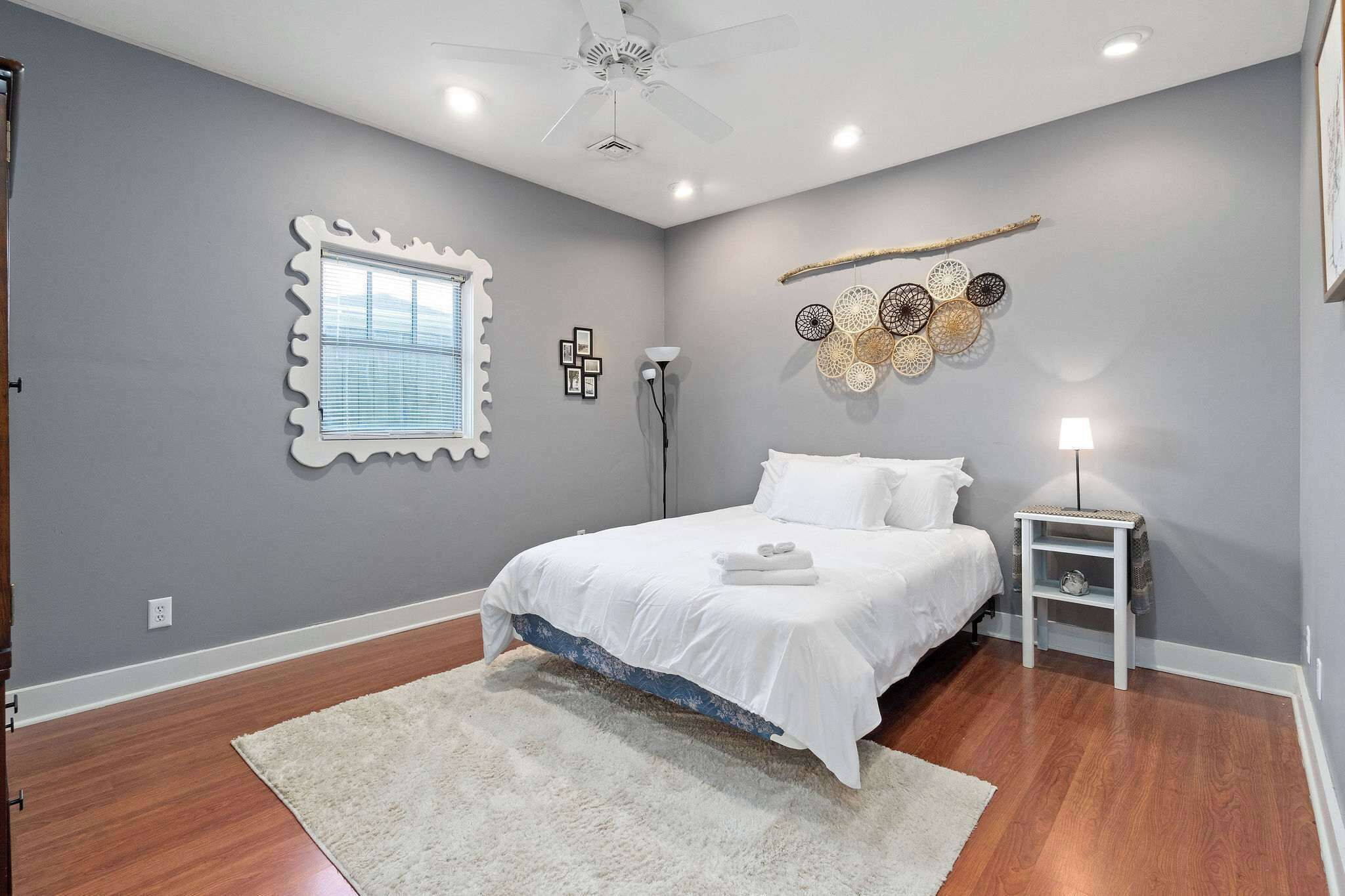 Una camera da letto con un letto, una ventola a soffitto, un comodino e decorazioni alle pareti.