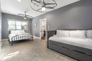 Un dormitorio con cama, sofá, ventilador de techo y ventana.