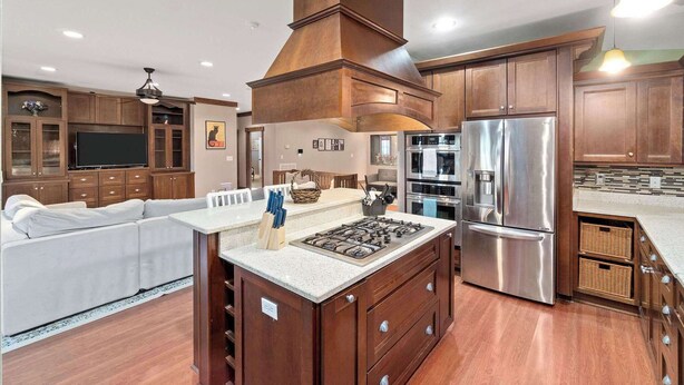 A modern kitchen with a central island, stainless steel appliances, and wooden cabinetry.