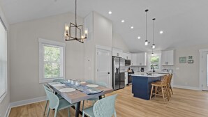 Una cocina moderna con armarios blancos, electrodomésticos de acero inoxidable y una isla central con taburetes de bar.