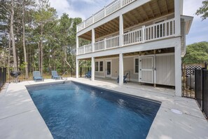 Una casa de dos plantas con piscina, un patio cubierto y un patio trasero cercado.