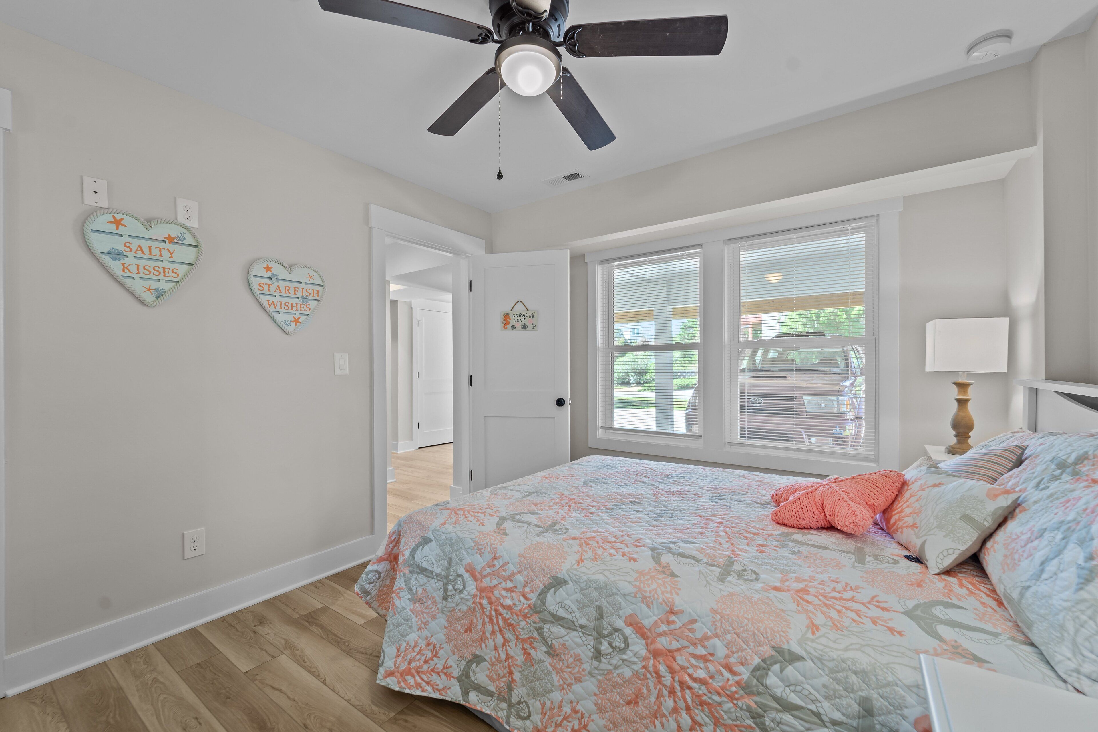 A bedroom with a bed, a ceiling fan, and two heart-shaped decorations on the wall.